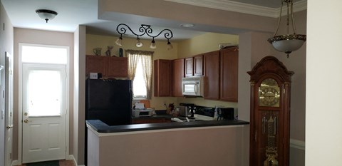 A kitchen with a black fridge and wooden cabinets.