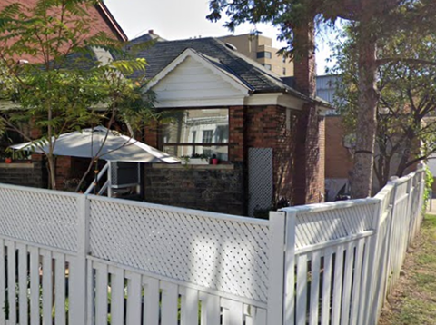 A white picket fence in front of a house.