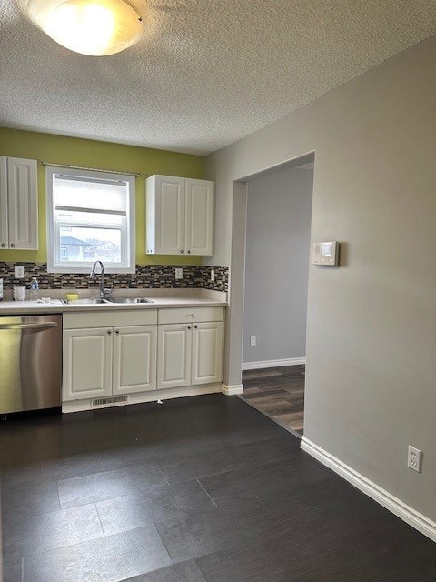 A kitchen with white cabinets and a stainless steel dishwasher.