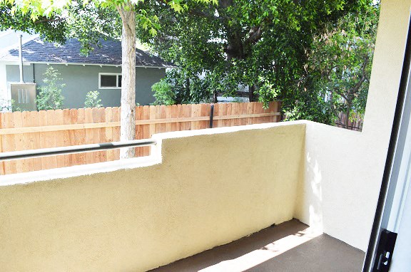 a balcony with a wooden fence and a house in the background