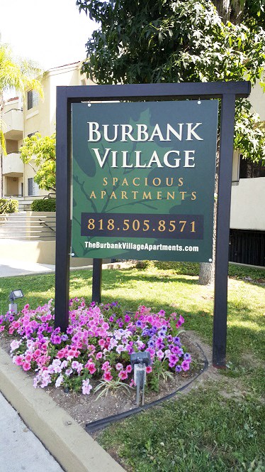 a sign for burbank village in front of flowers