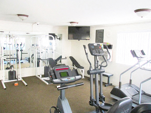 a gym with several machines and a tv in a room