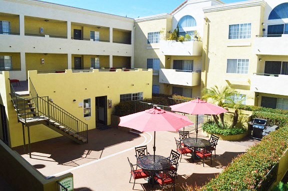 an apartment building with tables and umbrellas in the courtyard