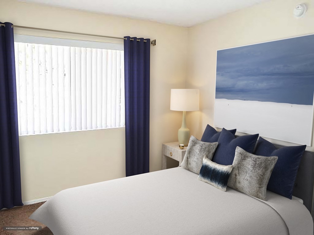 a bedroom with a bed and a window with blue and white pillows