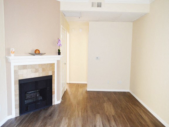 an empty living room with a fireplace and wooden floors