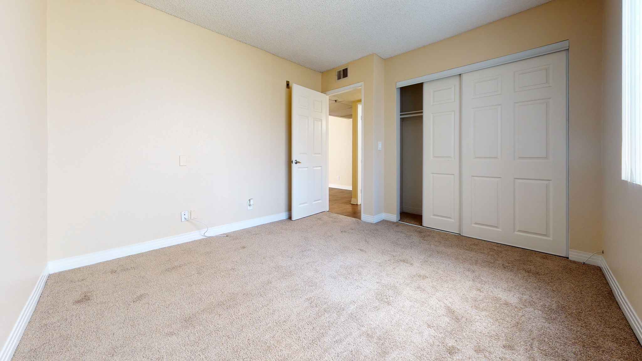 A room with a carpeted floor and two doors.