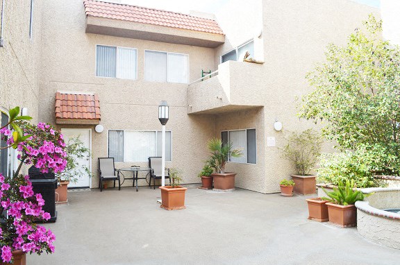 a patio with a table and chairs in front of a building
