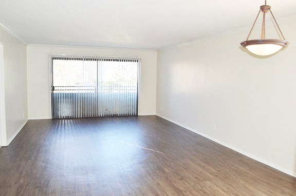 an empty living room with wood floors and a window