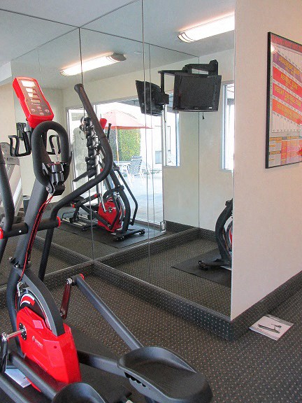 a gym with a red exercise bike and a mirror