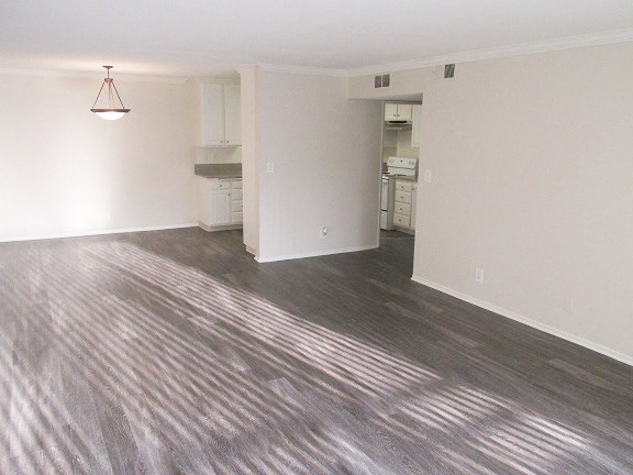 an empty living room and kitchen with a wood floor