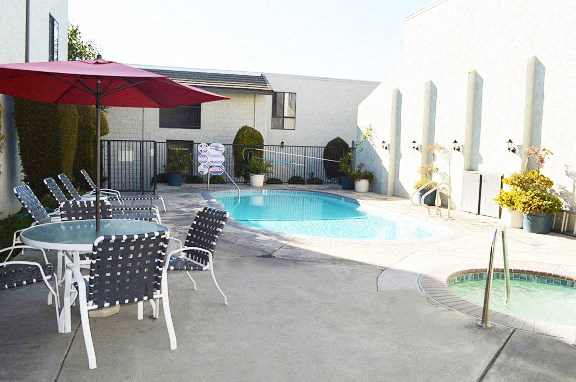 a swimming pool and patio with tables and chairs