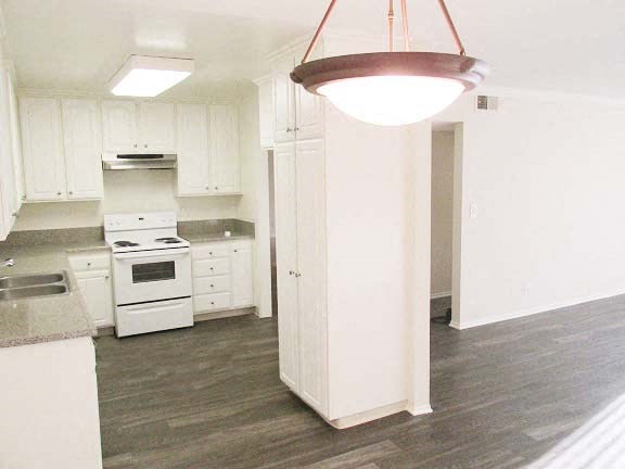 an empty kitchen with white cabinets and a light