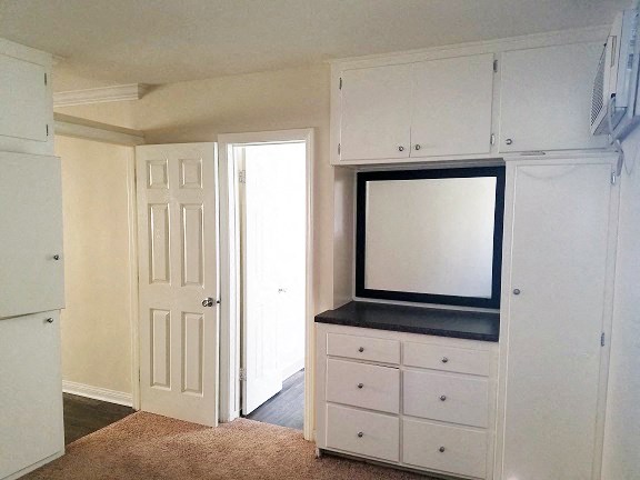 a white kitchen with white cabinets and a white door