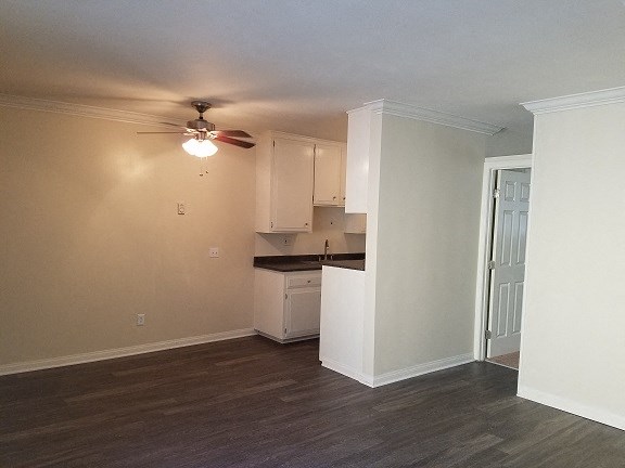 an empty living room and kitchen with a ceiling fan
