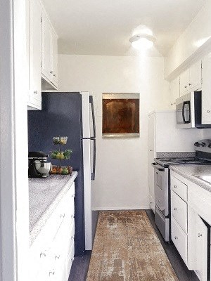 a white kitchen with white cabinets and a wooden floor