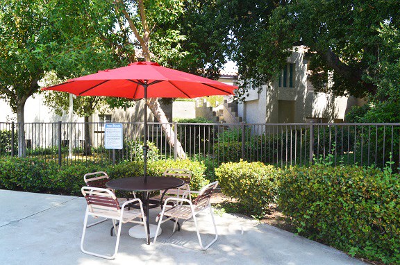 a patio table with a red umbrella and chairs