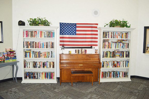 a living room with bookshelves and a dresser and an flag