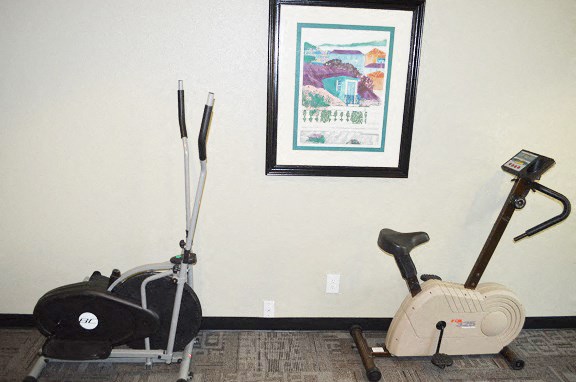 a home gym with two exercise machines and a picture on the wall