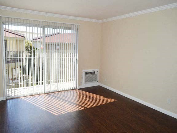 an empty living room with a heater and a window