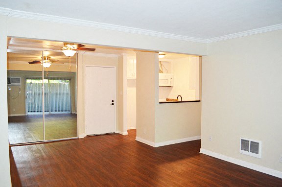an empty living room and kitchen with a ceiling fan