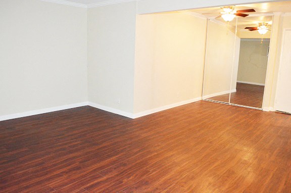an empty living room with wood flooring and white walls