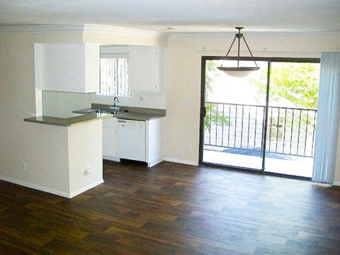 an empty living room with a kitchen and a sliding glass door