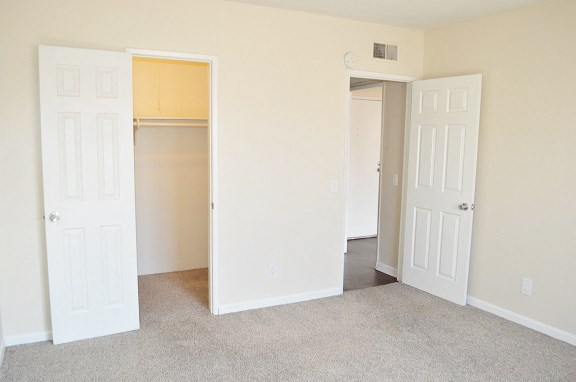an empty bedroom with three doors and a carpeted floor