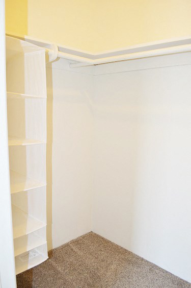 a small closet with white shelves and a white wall