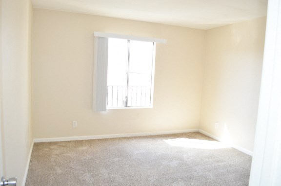 an empty room with a window and carpet