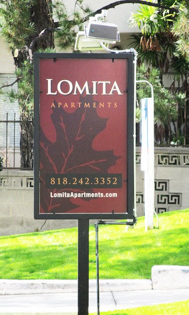 a sign for lomita apartments in front of a lawn