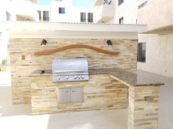 an outdoor kitchen with a grill and a stone wall
