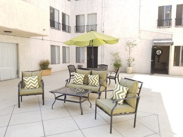 a patio with chairs and a yellow umbrella