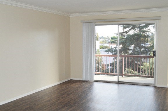 an empty living room with a sliding door to a balcony