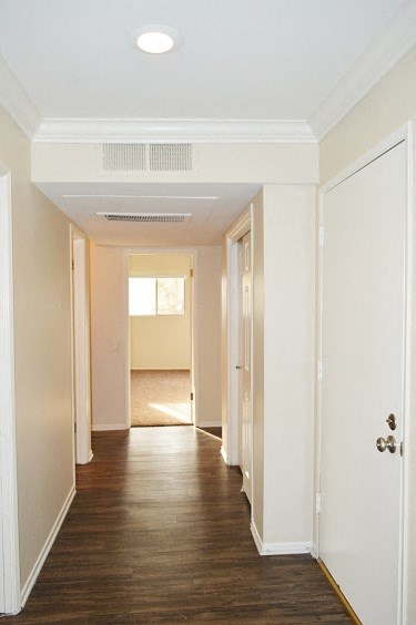 an empty hallway with a wood floor and white walls