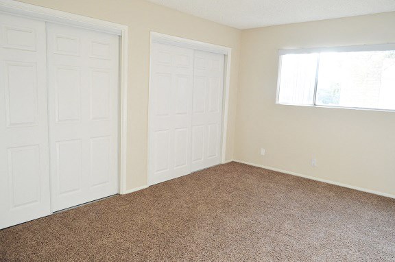 an empty room with two white doors and a window