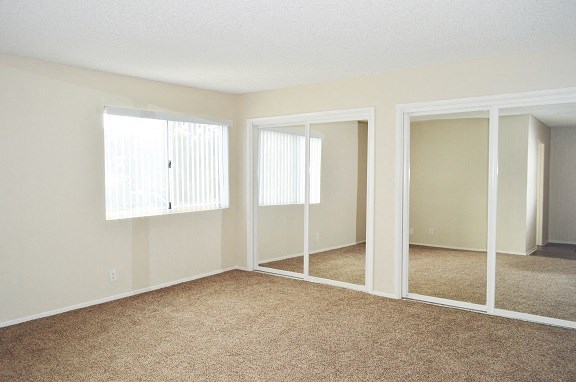 an empty living room with three mirrored doors