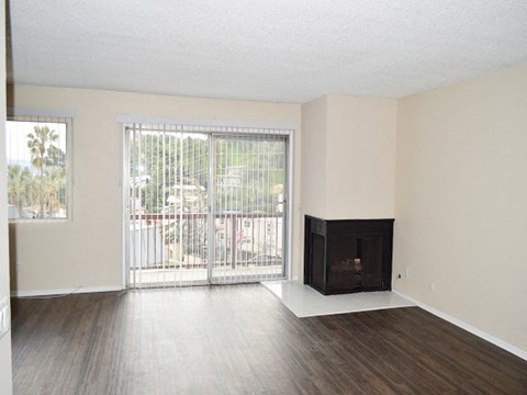 an empty living room with a fireplace and a balcony