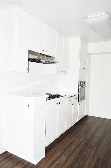 an empty kitchen with white cabinets and a stove