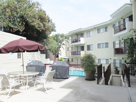 a patio with tables and chairs in front of an apartment building