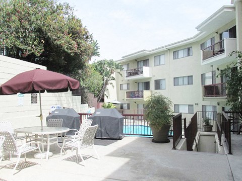 a patio with tables and chairs in front of an apartment building