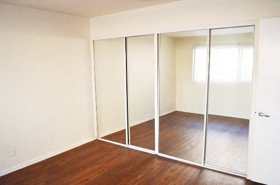 an empty room with a wood floor and mirrored closet doors