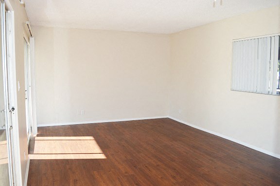 an empty living room with wood flooring and white walls