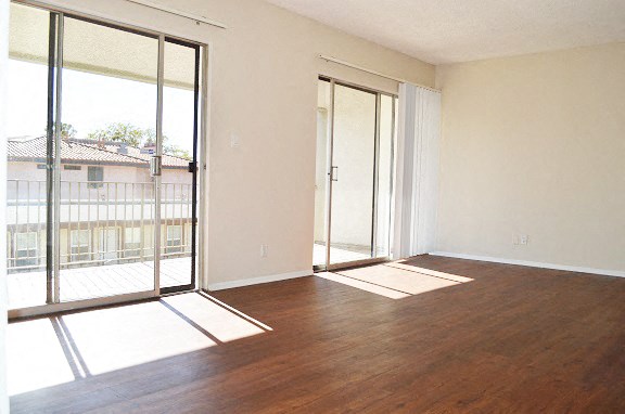 an empty living room with wood flooring and glass doors