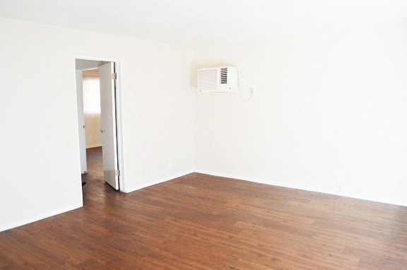 an empty room with wooden floors and a air conditioner on the wall