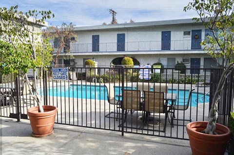 a swimming pool with a table and chairs behind a fence