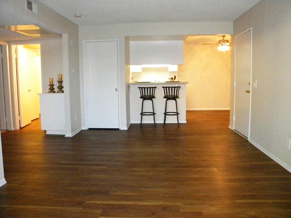 an empty living room and kitchen with wood floors