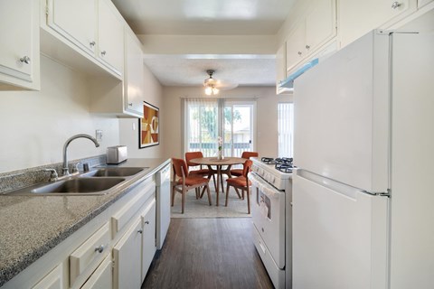 A kitchen with white appliances and a table with chairs.