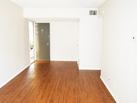 an empty living room with wood floors and white walls