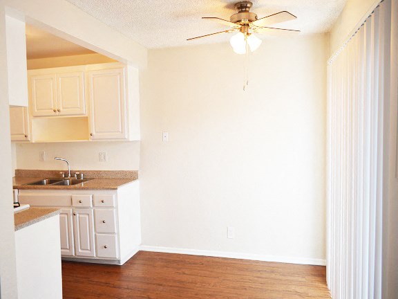 a kitchen with white cabinets and a ceiling fan