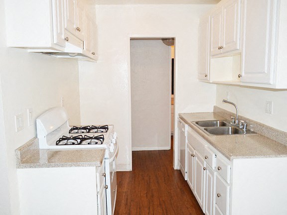 an empty kitchen with white cabinets and a sink